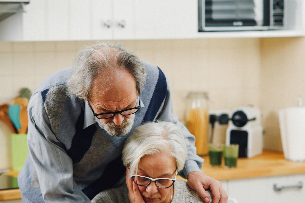 Elderly couple reading and talking together at home